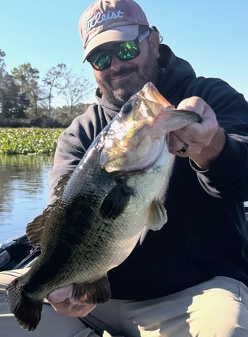 Angler holding a hefty largemouth bass caught from the boat